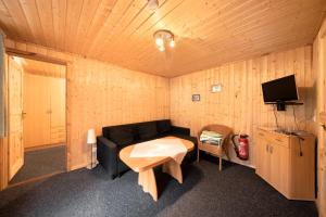 a living room with a black couch and a tv at Bungalow 37b - Kimbucht in Reichendorf
