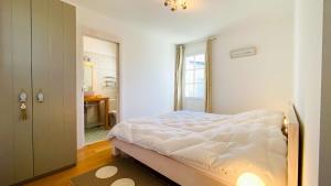 ein weißes Schlafzimmer mit einem Bett und einem Badezimmer in der Unterkunft Villa récente de style réthais avec piscine chauffée et jardin paysager in Le Bois-Plage-en-Ré