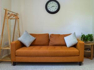 - un canapé brun dans le salon avec une horloge murale dans l'établissement Flat 1 - Uk50224, à Tetsworth