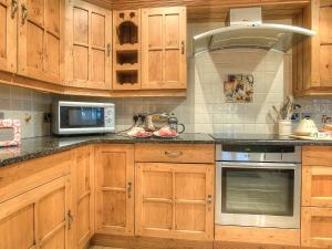 Little NewcastleにあるYr Hen Glowtyの木製のキャビネットとコンロ付きオーブンを備えたキッチン