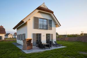 ein kleines weißes Haus mit einem Picknicktisch und Stühlen in der Unterkunft Reetland am Meer - Ihre Superior Reetdachvilla E28 - Zwei Schlafzimmer, Kamin & pure Wohlfühlatmosphäre in Dranske