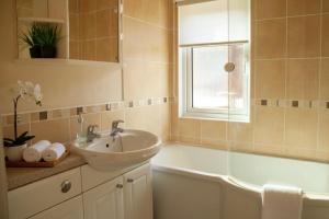 baño con lavabo, bañera y ventana en Saffron Lodge With Hot Tub, en Malton 18 fotos más