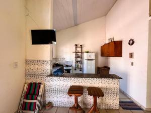a kitchen with a counter with two stools and a refrigerator at JGM chalés in Barreirinhas