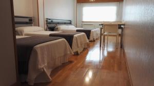 a row of beds in a room with a window at Toctoc Rooms in A Coruña