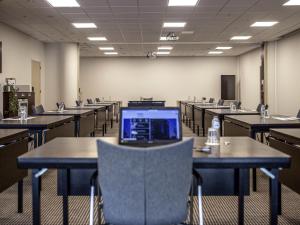 an empty classroom with tables and a laptop on top at Mercure Hotel Den Haag Central in The Hague