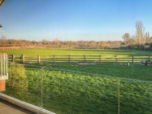 a view of a field from a window with a fence at Cedar Lodge in Old Buckenham