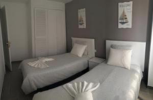 two beds in a room with white sheets at Casa Real in Playa Blanca