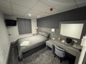 ブラックプールにあるWaverley Beach Hotelのベッド、デスク、モニターが備わるホテルルームです。