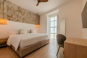 um quarto branco com uma cama e uma cadeira em Casa Encanto - Corazón de Getsemaní em Cartagena de Indias mais 75 fotografias