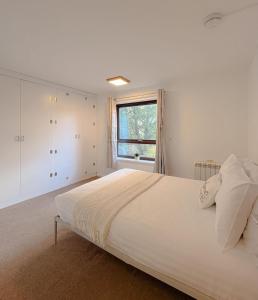 a white bedroom with a large bed and a window at Russet Grove in Earlham