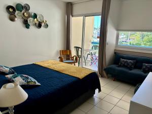 a bedroom with a bed and a couch and a window at Studio Carayou Pointe du Bout Les Trois-Ilets in Les Trois-Îlets