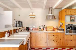 a large kitchen with wooden cabinets and a sink at Longère de charme avec piscine, proche océan in Lairoux +43 photos
