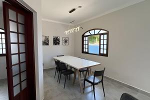 a dining room with a white table and chairs at Bertioga Sobrado Piscina 90m da Praia da Enseada in Bertioga