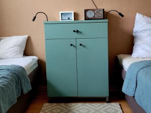 a blue cabinet with a clock on top of it next to two beds at Waldstraße 2 Windrose Kellenhusen in Kellenhusen