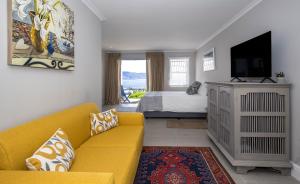 ein Wohnzimmer mit einer gelben Couch und einem Bett in der Unterkunft LIMA HOUSE, Seaforth, Simon's Town in Simonʼs Town