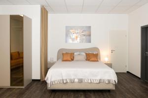 ein Schlafzimmer mit einem weißen Bett und orangefarbenen Kissen in der Unterkunft Arbio I Urban Apartment Zimmerstrasse in Leipzig