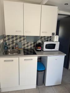 a kitchen with white cabinets and a microwave on a counter at Petit studio à la campagne proche cnpe paluel in Angerville-la-Martel