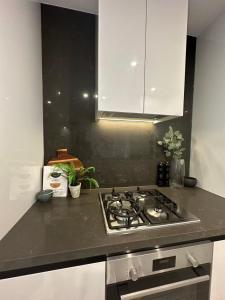 a kitchen with a stove and white cabinets at Meriton Parramatta in Sydney