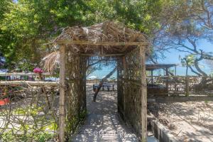 a wooden archway with a picnic table and a playground at Aptos em condo. com churrasq. e piscina na melhor localização de Porto Seguro – DVBs in Porto Seguro