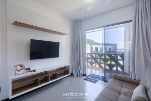 a living room with a flat screen tv on a wall at Aptos em condo. com churrasq. e piscina na melhor localização de Arraial d'Ajuda – DVBs in Coroa Vermelha