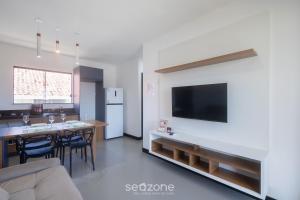 a kitchen and living room with a table and a television at Aptos em condo. com churrasq. e piscina na melhor localização de Porto Seguro – DVBs in Porto Seguro