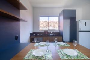 a kitchen with a table with two plates and wine glasses at Aptos em condo. com churrasq. e piscina na melhor localização de Arraial d'Ajuda – DVBs in Coroa Vermelha