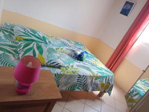a room with a bed and a table with a pink cup at la kaza in Le Morne Rouge