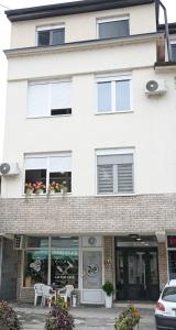 a white building with tables and chairs in front of it at Apartmani Slavica in Požega