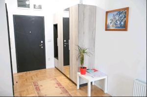 a hallway with a table and a black door at Apartmani Slavica in Požega
