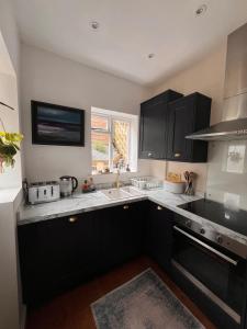 a kitchen with black cabinets and a sink at Two Bedroom House in the Heart of Winchester in Winchester +10 photos