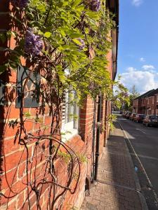 a brick building with purple flowers on the side of it at Two Bedroom House in the Heart of Winchester in Winchester