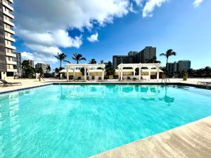 a large blue swimming pool with buildings in the background at Waikiki Seaside Monarch Paradise Hotel Room Greenery Mountain View in Honolulu