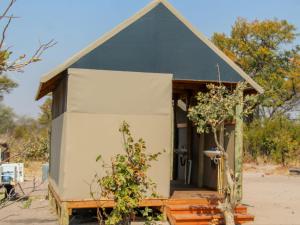 a small black and white house with a porch at Khwai Game Lodge and Campsite in Khwai