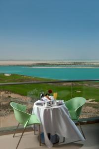 Ein Tisch mit grünen Stühlen und Blick auf das Meer in der Unterkunft Crowne Plaza Yas Island by IHG in Abu Dhabi