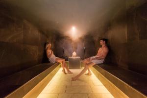 a man and a woman sitting on a bench at Mirabell Dolomites Hotel - Luxury Ayurveda & Spa in Valdaora