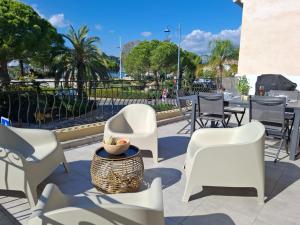 un grupo de sillas blancas y una mesa y sillas en Anatole - T3 - Moderne - Climatisé - 1er étage - Très grande terrasse 35 M2 - Vue magnifique et dégagée, en Saint-Mandrier-sur-Mer