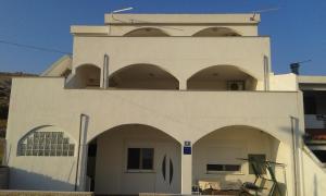 a white building with arches in front of it at Apartments Markulincic in Novalja