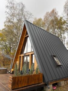 ein winziges Haus mit schwarzem Dach auf einer Terrasse in der Unterkunft Wildcabinpanoramic Marisel in Mărişel
