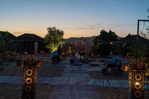 a group of people sitting in a courtyard at sunset at Stargazing Merzouga Camp in Merzouga