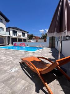 una silla y una sombrilla junto a la piscina en White house Paradise, en Bihać