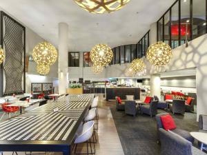 a lobby with tables and chairs and chandeliers at ibis Melbourne Hotel and Apartments in Melbourne