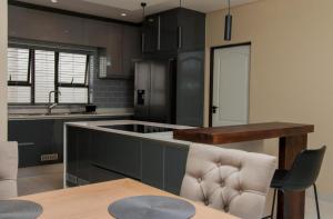 a kitchen with black cabinets and a table and chairs at Simphiwe Guesthouse in Manzini