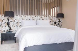 a bedroom with a white bed and two lamps at Simphiwe Guesthouse in Manzini