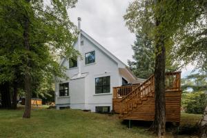 a large white house with a large wooden deck at La Pionnière - 5 chambres - 13 personnes in Saint-Férréol-les-Neiges