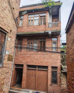 a brick building with two doors and a balcony at 'Timeless Bhaktapur Home' in Bhaktapur