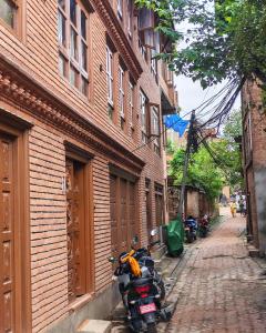 a motorcycle parked on a street next to a brick building at 'Timeless Bhaktapur Home' in Bhaktapur