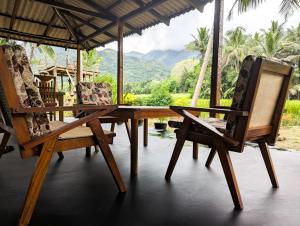 una mesa y sillas en un porche con montañas al fondo en Crystal Water Inn, en Bibile 36 fotos más