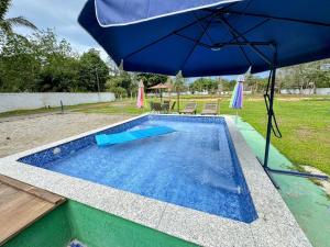 ein blauer Regenschirm neben einem Pool in der Unterkunft Ohana in Peruíbe + 9 Fotos