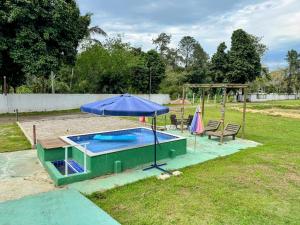 einen Pool mit Sonnenschirm und Spielplatz in der Unterkunft Ohana in Peruíbe