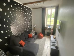 a living room with a black couch and orange pillows at Le Manoir aux Volets Verts with Hot Tub in Salerm